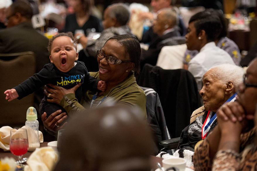 Marilyn Akinmurel of Lanum, Md. holds her nephew Adonis, 6, who yawns during the Annual Centenarian Salute Luncheon to celebrate their family member Charlotte Wilkins, right, and other District residents over one hundred years of age held at Gallaudet University, Washington, D.C., Monday, March 24, 2014. (Andrew Harnik/The Washington Times)