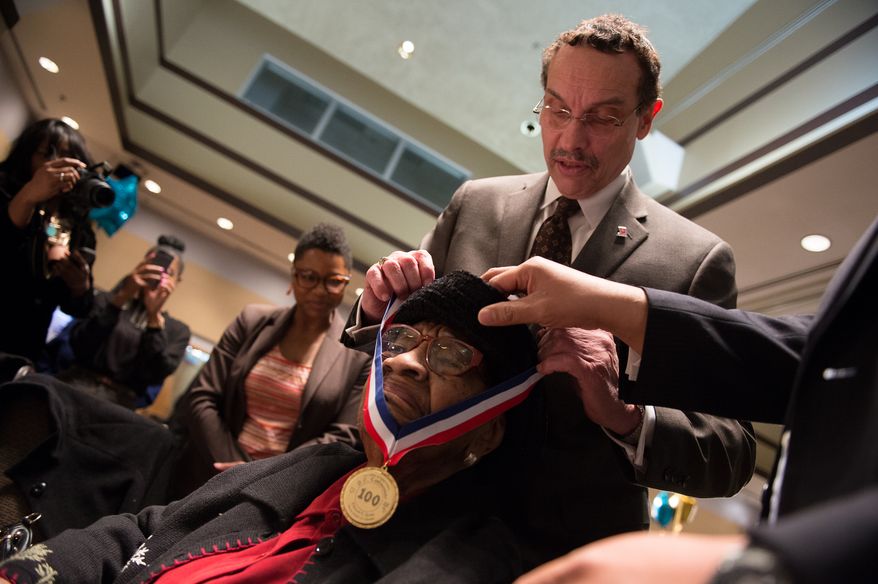 Washington, D.C. Mayor Vincent Gray gives a medal to Lula Mae Henderson Scott for being over a hundred years old during the Annual Centenarian Salute Luncheon for District residents held at Gallaudet University, Washington, D.C., Monday, March 24, 2014. (Andrew Harnik/The Washington Times)