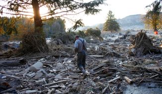 Steve Skaglund walks across the rubble on the east side of Saturday&#39;s fatal mudslide near Oso, Wash., Sunday, March 23, 2014. (AP Photo /The Herald, Genna Martin)