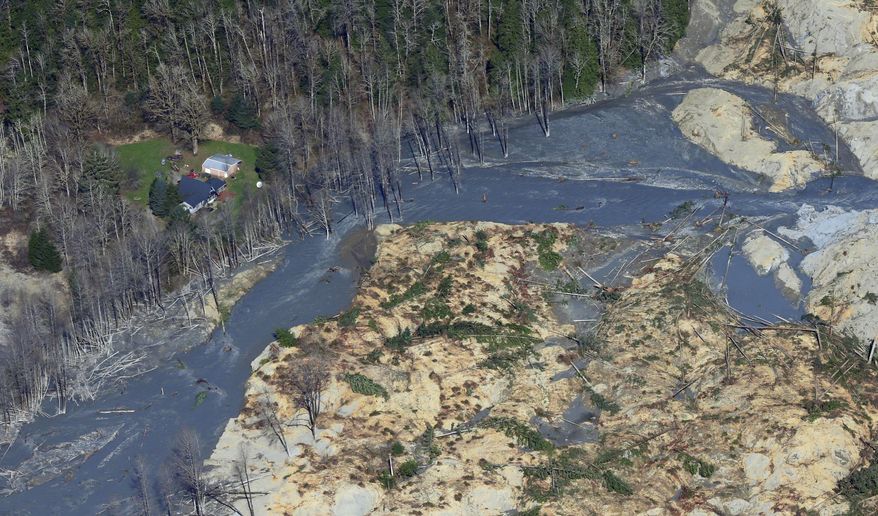 An intact house sits at left at the edge of the massive mudslide that killed at least eight people and left dozens missing is shown in this aerial photo, Monday, March 24, 2014, near Arlington, Wash. The search for survivors grew Monday, raising fears that the death toll could climb far beyond the eight confirmed fatalities. (AP Photo/Ted S. Warren)