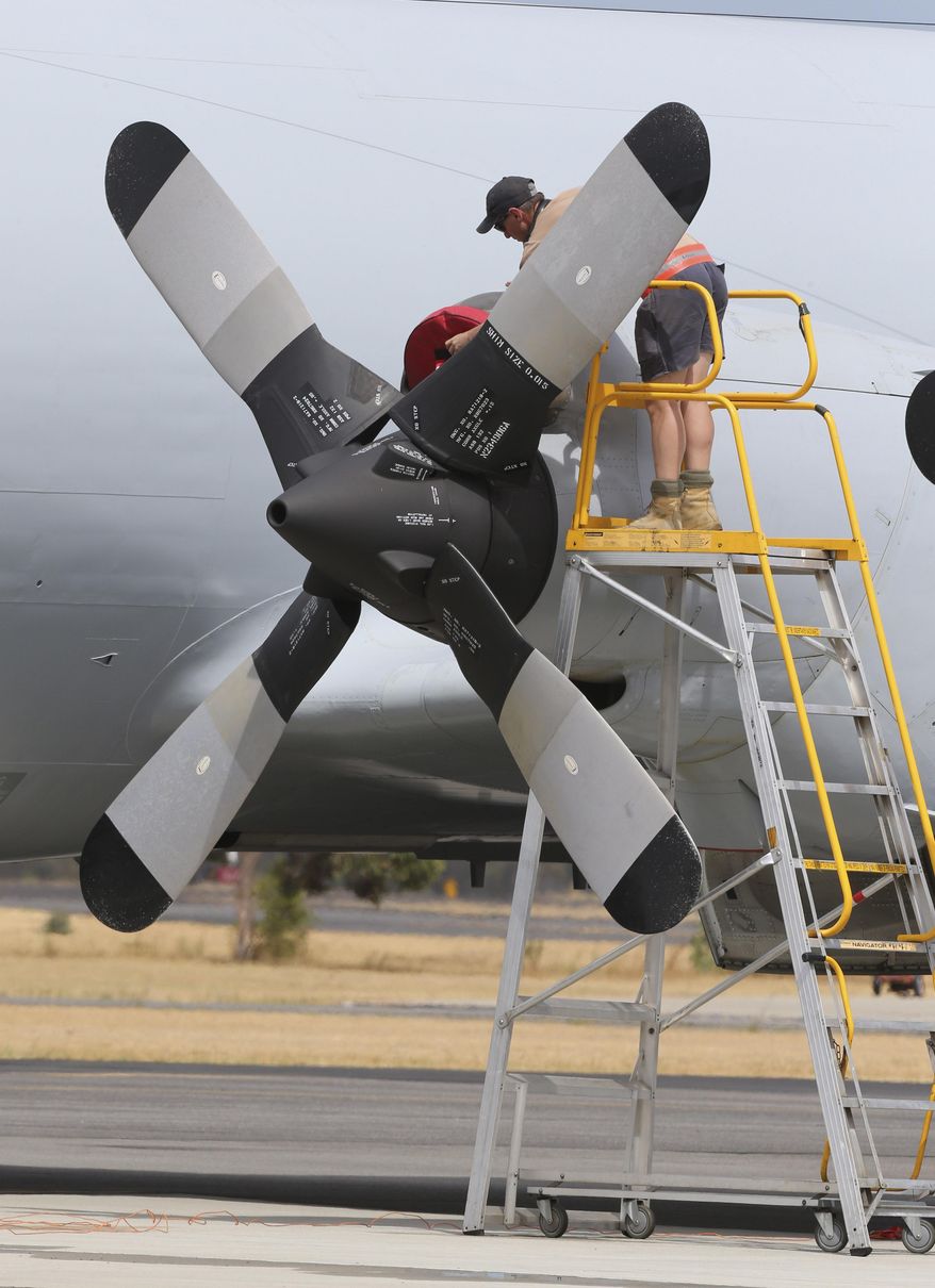 A ground crew works on a Royal Australian Air Force AP-3C Orion on the tarmac in Perth, Australia, Tuesday, March 25, 2014. All search and rescue flights for the missing Malaysia Airlines flight MH370 were canceled for Tuesday due to bad wether in the search area. (AP Photo/Rob Griffith)