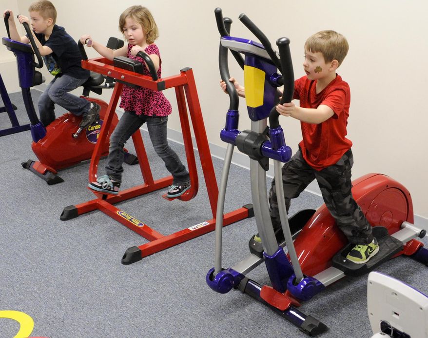 FOR RELEASE SATURDAY, MARCH 29, 2014, AT 12:01 A.M. CDT. - In this photo from March 18, 2014, kindergartners from left, Brogan Wasurick on the junior exercise bike, Alexis Brey on the moon walker and Aiden Schanilec on the junior elliptical, workout to music in the cardio room with miniature exercise equipment at O.H. Shultz Elementary School in Mishicot, Wis., during physical education class. (AP Photo/Herald-Times Reporter, Sue Pischke) NO SALES.