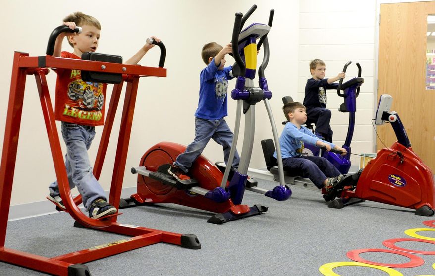 FOR RELEASE SATURDAY, MARCH 29, 2014, AT 12:01 A.M. CDT. - In this photo from March 18, 2014, kindergartners from left, Gavin Dordlinger on the moon walker, Curtis Campion on the junior elliptical, Sawyer Sand on the junior rower and Owen Moore on the junior exercise bike workout to music in the cardio room with miniature exercise equipment at O.H. Shultz Elementary School in Mishicot Wis., during physical education class. (AP Photo/Herald-Times Reporter, Sue Pischke) NO SALES.