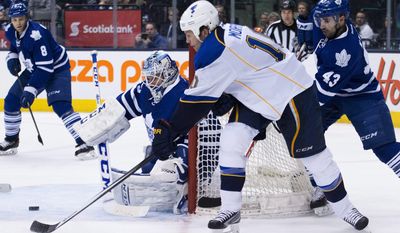 Toronto Maple Leafs goalie Jonathan Bernier, hugs the goal post as St. Louis Blues forward Brenden Morrow, second right, tries for the wrap around past Maple Leafs forward Nazem Kadri during third period NHL hockey action in Toronto on Tuesday, March 25, 2014. (AP Photo/The Canadian Press, Nathan Denette)