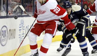 Detroit Red Wings&#39; Drew Miller, left, works for the puck against Columbus Blue Jackets&#39; James Wisniewski  in the first period of an NHL hockey game in Columbus, Ohio, Tuesday, March 25, 2014. (AP Photo/Paul Vernon)