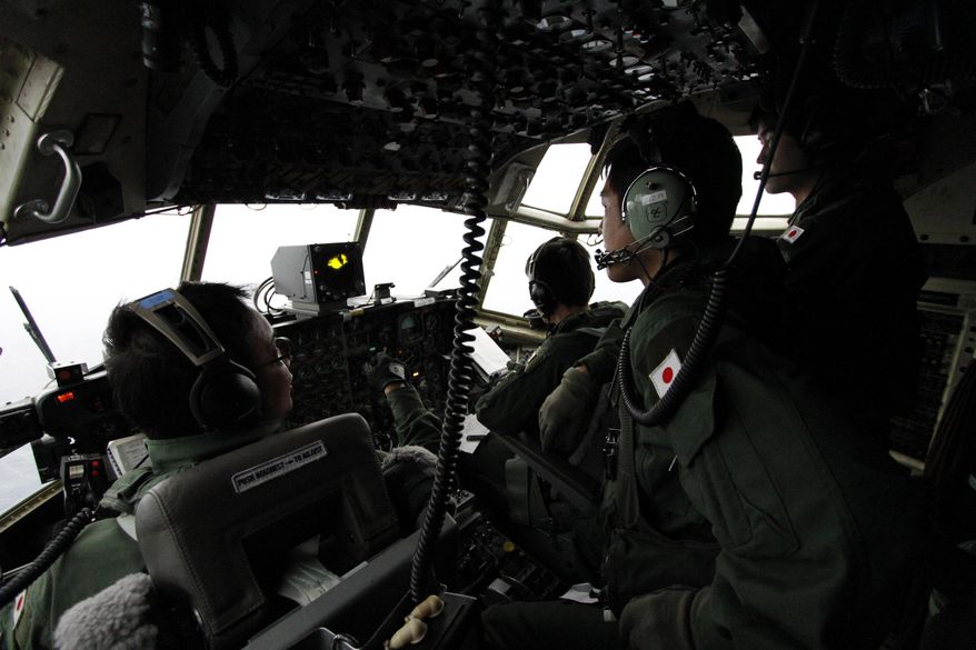 FILE - In this March 21, 2014 file photo, Japanese Air Self-Defense Force's Capt. Junichi Tanoue, left, co-pilot Ryutaro Hamahira, second from left, and engineer Noriyuki Yamanouchi, second from right, scan the ocean aboard a C130 aircraft while it flies over the southern search area in the southeastern Indian Ocean, 200 to 300 kilometers (124 to 186 miles) south of Sumatra, Indonesia. Not one object has been recovered from the missing airliner that Malaysian officials are now convinced plunged into the southern Indian Ocean 17 days ago. Some of the pieces are likely 3,500 meters (11,500 feet) underwater. Others are bobbing in a fickle system of currents that one oceanographer compares to a pinball machine. And by now, they could easily be hundreds of kilometers (miles) away from each other. (AP Photo/Koji Ueda, File)
