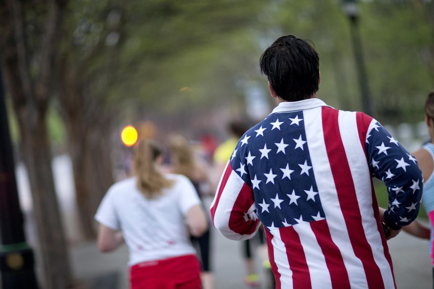 Conn Jackson, of Atlanta, right, wears a shirt decorated with the flag of the United States as he takes part in an organized moment of silence and memorial run to show solidarity with victims of the Boston Marathon bombing, Tuesday, April 16, 2013, in Atlanta. The explosions Monday afternoon killed at least three people and injured more than 140. (AP Photo/David Goldman)
