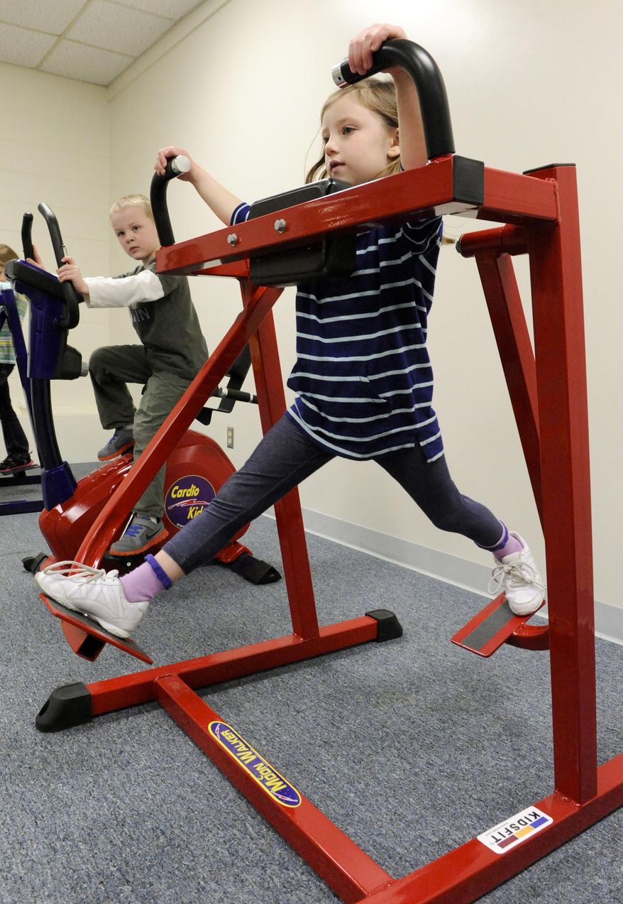 FOR RELEASE SATURDAY, MARCH 29, 2014, AT 12:01 A.M. CDT. - In this photo taken March 18, 2014, kindergartner Tessa Kamien exercises on the moon walker as she and her kindergarten class workout to music in the cardio room with miniature exercise equipment at O.H. Shultz Elementary School in Mishicot during physical education class in Mishicot, Wis. (AP Photo/Herald-Times Reporter, Sue Pischke) NO SALES.
