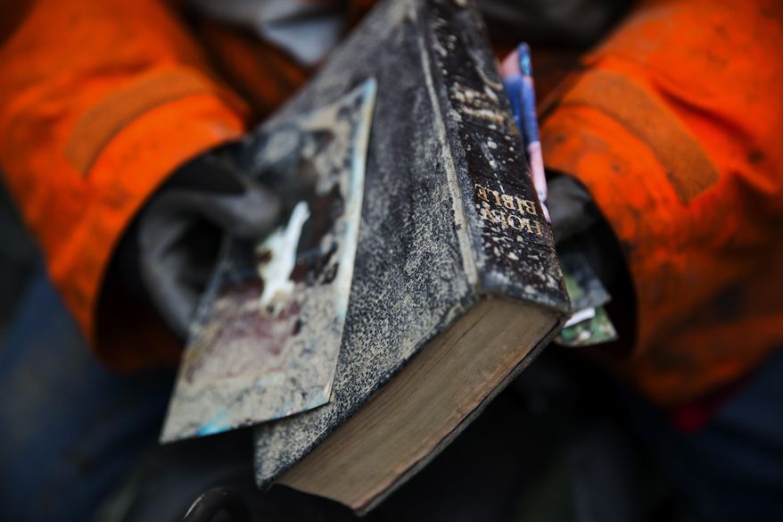 Elaine Young holds a Bible that she pulled out of the debris field caused by a massive mudslide on Saturday, above the North Fork of the Stillaguamish River onto Highway 530, as recovery efforts continue near Oso, Wash., on Tuesday, March 25, 2014. A scientist working for the government had warned 15 years ago about the potential for a catastrophic landslide in the community where the collapse of a rain-soaked hillside over the weekend killed at least 14 people and left scores missing. (AP Photo/The Seattle Times, Marcus Yam) SEATTLE OUT; USA TODAY OUT; MAGS OUT; TELEVISION OUT; NO SALES; MANDATORY CREDIT TO BOTH THE SEATTLE TIMES AND THE PHOTOGRAPHER