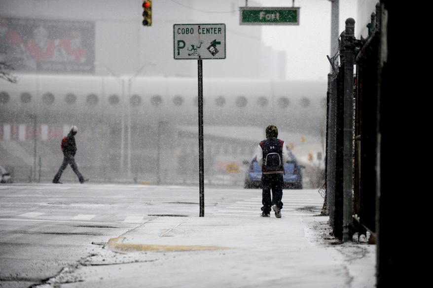 People walk as snow falls on Tuesday, March 25, 2014, in Detroit. Up to an inch of snow is expected in the Detroit area on Tuesday. Detroit has seen its second-snowiest winter season on record, with 90.7 inches falling. The record is 93.6 inches set in 1880-1881. (AP Photo/Detroit News, David Coates) DETROIT FREE PRESS OUT; HUFFINGTON POST OUT; MANDATORY CREDIT