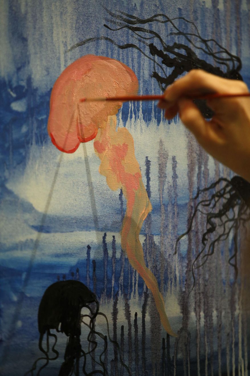 In this Tuesday, March 25, 2014 photo, Christine Bailey, of Philadelphia, paints a jellyfish during a Paint Nite event at the Field House sports bar in Philadelphia. Cities like Philadelphia, Boston and New York are offering a creative way to socialize and bring out your inner artist: Paint Nite. A ticket buys you a small canvas, brushes, paints and an easy two-hour lesson at a neighborhood bar. (AP Photo/Matt Slocum)