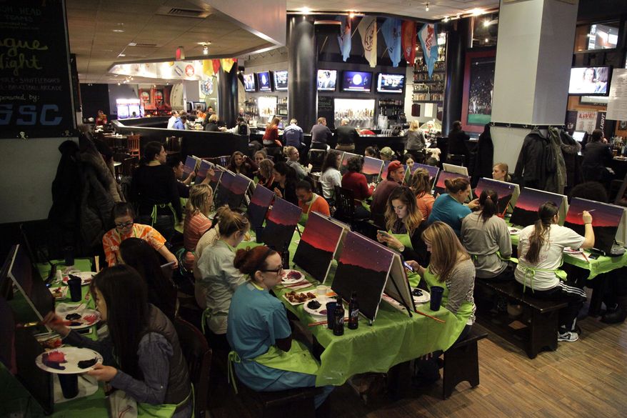 In this Tuesday, March 25, 2014 photo, participants paint a sunset during a Paint Nite event at the Field House sports bar in Philadelphia. Cities like Philadelphia, Boston and New York are offering a creative way to socialize and bring out your inner artist: Paint Nite. A ticket buys you a small canvas, brushes, paints and an easy two-hour lesson at a neighborhood bar. (AP Photo/Matt Slocum)