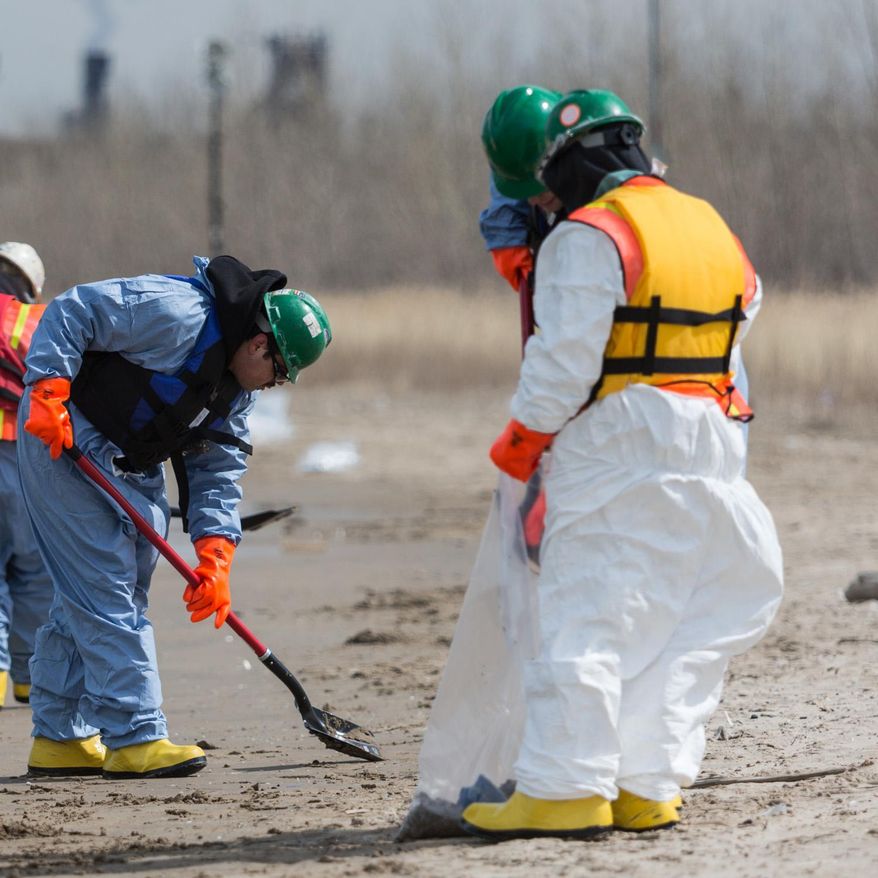 In this March 25, 2014 photo, a worker combs the beach in Whiting, Ind. Crews for oil giant BP worked Tuesday to clean up an undetermined amount of crude oil that spilled into Lake Michigan and affected about a half-mile section of shoreline near Chicago following a malfunction at BP's northwestern Indiana refinery, officials said. (AP Photo/Sun-Times Media, Jim Karczewski)  MANDATORY CREDIT, MAGS OUT, NO SALES