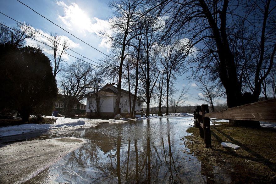 In this March 24, 2014 photo, the Grand River overflows part of its east bank submerging a section of road in front of a home in Grand Rapids, Mich. The river is expected to drop Wednesday before rising again by the middle of next week. (AP Photo/MLive.com, Andrew Kuhn) ALL LOCAL TV OUT; LOCAL TV INTERNET OUT
