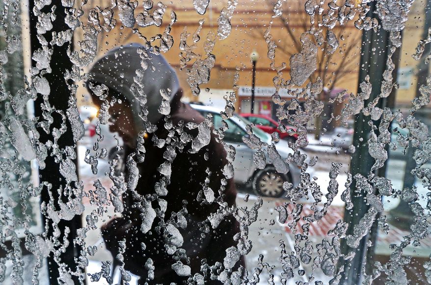 Ice and snow accumulate on a door at Bristol Community College as a student enters during a spring snowstorm on campus in New Bedford, Mass., Wednesday, March 26, 2014. The spring storm brought high winds that whipped snow across portions of Massachusetts and eastern Maine Wednesday, causing near-whiteout conditions on Cape Cod and roiling the Atlantic as it moved up the coast. (AP Photo/Standard Times, Peter Pereira)