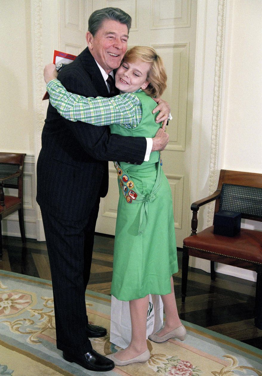 FILE - In this Jan. 9, 1986, file photo, President Ronald Reagan hugs Elizabeth Brinton, 14, of Falls Church, Va., during a meeting at the White House in Washington. Brinton who has held a Girl Scout cookie sales record for decades says she has no problem giving up her cookie crown to an Oklahoma girl who broke her record. Brinton set the one year sales record of 18,000 boxes as a teenager in the 1980s. She sold outside Metro stations in the Washington area and in 1986 even sold cookies to Reagan. Now a mother of two living in Alabama, Brinton says the new cookie queen, Katie Francis of Oklahoma City, called her to ask for advice. (AP Photo/Charles Tasnadi, File)