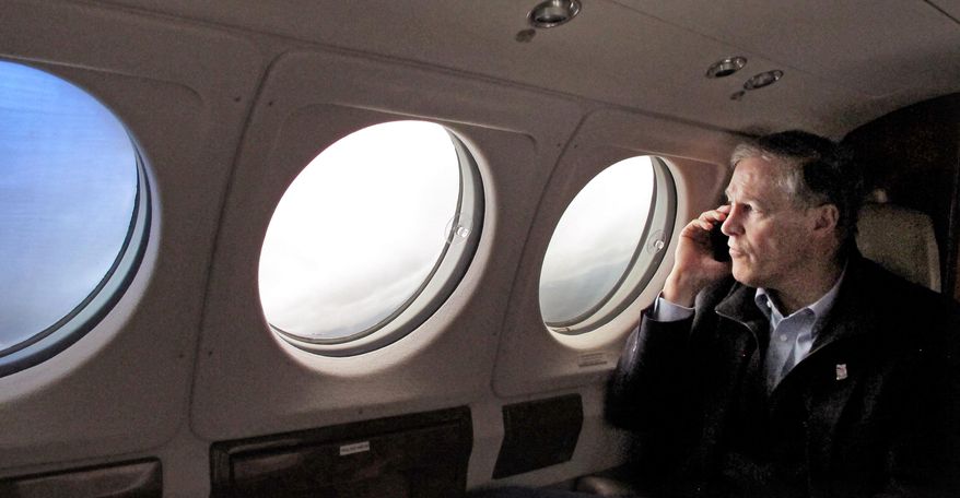 Gov. Jay Inslee speaks on the phone with a family member of a mudslide victim as he flies to the Snohomish County Emergency Operations Center in Everett, Wash., Wednesday, March 26, 2014. Sixteen bodies have been recovered, but authorities believe at least 24 people were killed. And scores of others are still unaccounted for, although many of those names were believed to be duplicates or people who escaped safely. (AP Photo/Rachel La Corte)
