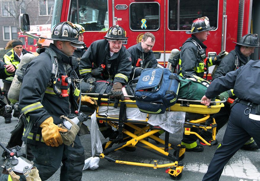 Firefighters scream for an ambulance as they work on and rush an injured firefighter on a stretcher down Beacon Street, Wednesday, March 26, 2014, in Boston. Firefighters responded to a four-story brownstone fire. A Boston city councilor said two firefighters have died in the fire. (AP Photo/The Boston Globe, Jim Davis) MANDATORY CREDIT. NO SALES. MAGAZINES OUT. INTERNET OUT. ARCHIVE OUT. BOSTON HERALD OUT, QUINCY OUT; NO SALES.
