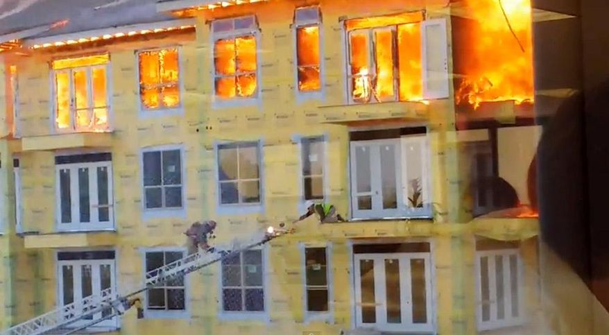 In this image taken from video provided by Karen Jones, a worker reaches for an extension ladder to escape a raging fire as firefighters battle a five-alarm blaze at a construction site Tuesday, March 25, 2014, in Houston. The cellphone video, shot by Karen Jones from her nearby office, shows the dramatic rescue of the worker from the burning apartment complex that was under construction. (AP Photo/Karen Jones) NO SALES