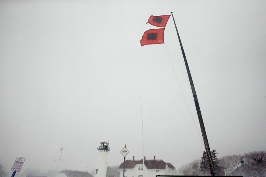Hurricane flags fly over U.S. Coast Guard Lifeboat Station Chatham and Chatham Light, in Chatham, Mass., Wednesday, March 26, 2014. A blizzard warning is in effect for Cape Cod, Martha's Vineyard and Nantucket as forecasters warned of wind gusts as high as 70 miles per hour. (AP Photo/Stephan Savoia)
