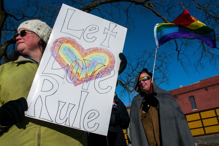 Grand Blanc resident Erin Rockafellow, 33, left, holds a sign up as Flint resident Jackie Mercer, back right, waves a rainbow-colored flag during a pro-gay marriage rally held by the Unitarian Universalist Church of Flint on Wednesday, March 26, 2014 outside of the Genesee County Courthouse in Flint, Mich. A federal appeals court Tuesday put an indefinite halt to gay marriage in Michigan while it takes a longer look at the decision overturning a 2004 ban. (AP Photo/The Flint Journal, Jake May) LOCAL TV OUT; LOCAL INTERNET OUT