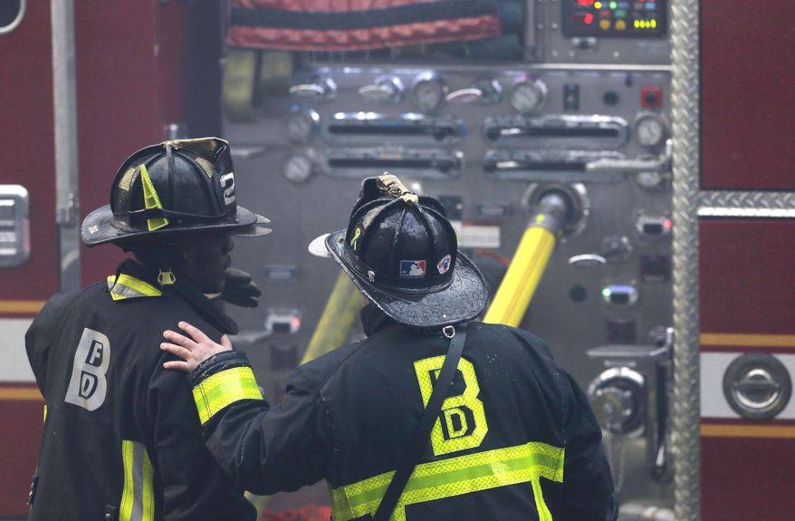 ADDS LAST SENTENCE - A firefighter places his hand on the shoulder of another at the scene of a multi-alarm fire at a four-story brownstone in the Back Bay neighborhood near the Charles River, Wednesday, March 26, 2014 in Boston. A Boston city councilor said two firefighters have died in a fire that ripped through a brownstone. (AP Photo/Steven Senne)
