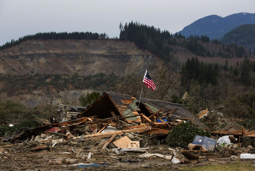 A damaged home sits in the debris field caused by Saturday's massive mudslide above the North Fork of the Stillaguamish River onto Highway 530, as recovery efforts continue near Oso, Wash., on Tuesday, March 25, 2014. A scientist working for the government had warned 15 years ago about the potential for a catastrophic landslide in the community where the collapse of a rain-soaked hillside over the weekend killed at least 14 people and left scores missing. (AP Photo/The Seattle Times, Marcus Yam) SEATTLE OUT; USA TODAY OUT; MAGS OUT; TELEVISION OUT; NO SALES; MANDATORY CREDIT TO BOTH THE SEATTLE TIMES AND THE PHOTOGRAPHER