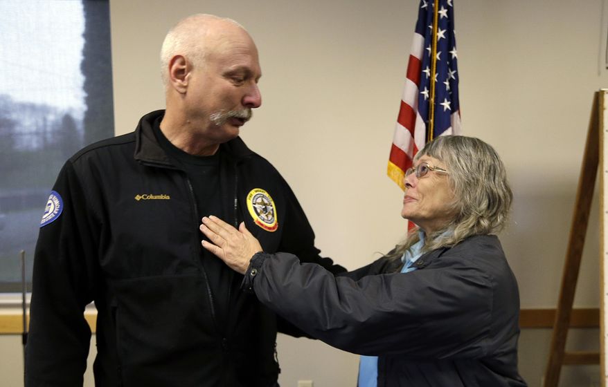 Robin Youngblood, right, smiles after embracing Snohomish County helicopter crew chief Randy Fay, who helped rescue her from the scene of a deadly mudslide days earlier, Wednesday, March 26, 2014, in Arlington, Wash. Youngblood was home when the mudslide hit, moving her house a quarter-mile where she was able to find her way out of the rubble. She heard that Fay was addressing a news conference and showed-up afterwards to thank him. Sixteen bodies have been recovered, but authorities believe at least 24 people were killed. Scores of others are still unaccounted for. (AP Photo/Elaine Thompson)