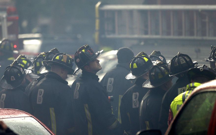 ADDS LAST SENTENCE - Firefighter look on at the scene of a multi-alarm fire at a four-story brownstone in the Back Bay neighborhood near the Charles River, Wednesday, March 26, 2014, in Boston. A Boston city councilor said two firefighters have died in a fire that ripped through a brownstone. (AP Photo/Steven Senne)