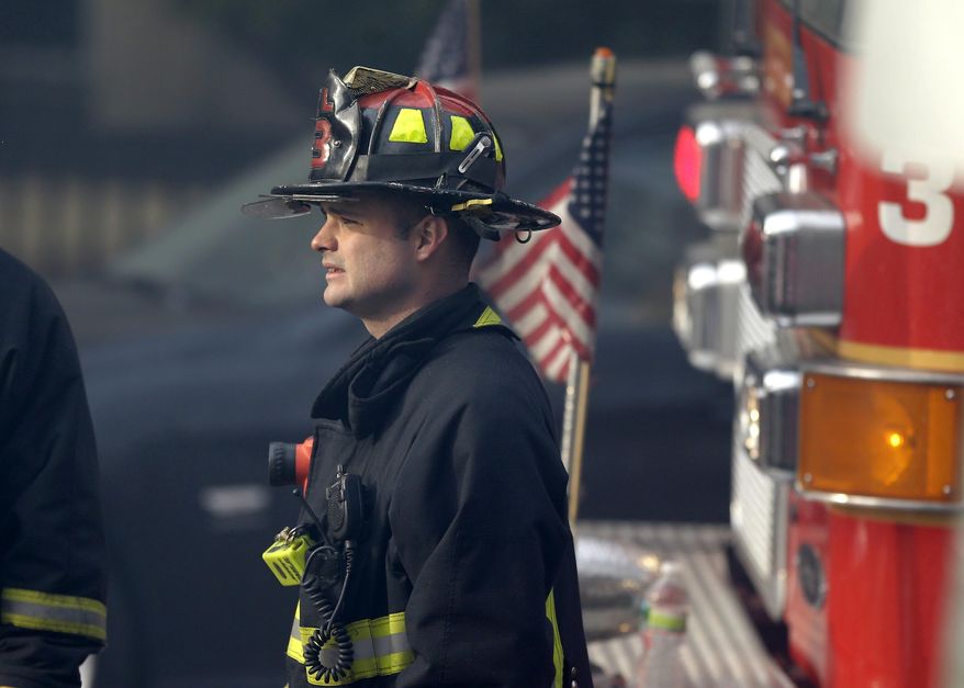ADDS LAST SENTENCE - A firefighter looks on at the scene of a multi-alarm fire at a four-story brownstone in the Back Bay neighborhood near the Charles River, Wednesday, March 26, 2014, in Boston. A Boston city councilor said two firefighters have died in a fire that ripped through a brownstone. (AP Photo/Steven Senne)