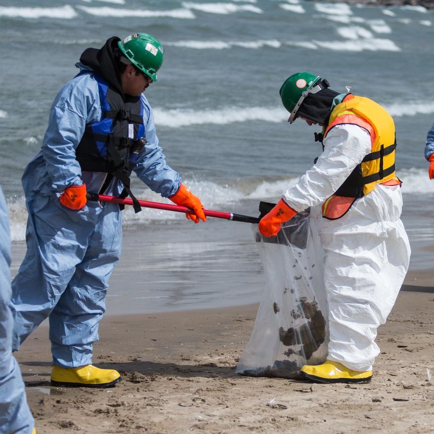 In this March 25, 2014 photo, a worker dumps soil into a bag in Whiting, Ind. Crews for oil giant BP worked Tuesday to clean up an undetermined amount of crude oil that spilled into Lake Michigan and affected about a half-mile section of shoreline near Chicago following a malfunction at BP's northwestern Indiana refinery, officials said. (AP Photo/Sun-Times Media, Jim Karczewski)  MANDATORY CREDIT, MAGS OUT, NO SALES