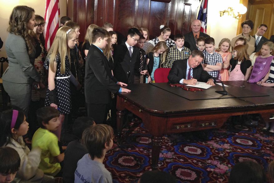 Ohio Gov. John Kasich signs a bill to grant school districts additional calamity days before a group of students at the Statehouse in Columbus, Ohio. Snow, ice and harsh temperatures caused many districts across Ohio to exhaust the school year's five allowable calamity days, most commonly called "snow days," in which schools can close without making up the lost instructional time. Ohio schools will receive four extra calamity days this year under the bill. (AP Photo/Ann Sanner)