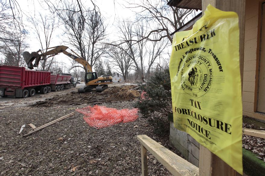 A excavator removes debris from a demolished house next to a house with a foreclosure notice in Detroit’s Brightmoor area Monday, March 24, 2014, in Detroit. For years, Brightmoor area residents pleaded with the city to demolish vacant homes that scavengers have stripped of wiring and plumbing and anything of value. Some structures are already gone, and now officials aim to do much more, possibly tearing down as many as 450 empty houses each week across more than 20 square miles of this bankrupt city _ a vast patchwork of rotting homes comparable to the size of Manhattan. (AP Photo/Paul Sancya)