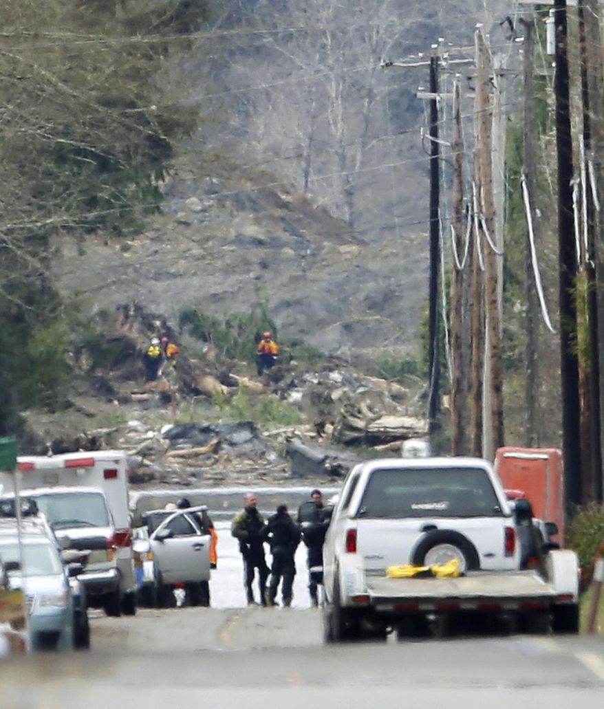 Workers can be seen in the background of the staging area on the east edge of the massive mudslide that struck near Darrington, Wash. on Saturday, killing at least 16 people and leaving dozens missing, Wednesday, March 26, 2014. (AP Photo/Ted S. Warren)