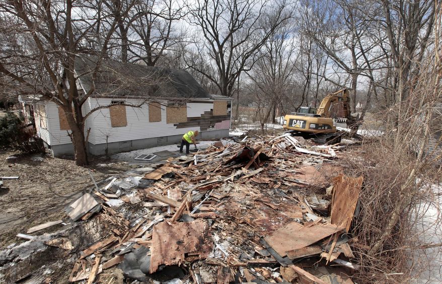 A excavator tears down a house in Detroit’s Brightmoor area Monday, March 24, 2014, in Detroit. For years, Brightmoor area residents pleaded with the city to demolish vacant homes that scavengers have stripped of wiring and plumbing and anything of value. Some structures are already gone, and now officials aim to do much more, possibly tearing down as many as 450 empty houses each week across more than 20 square miles of this bankrupt city _ a vast patchwork of rotting homes comparable to the size of Manhattan. (AP Photo/Paul Sancya)