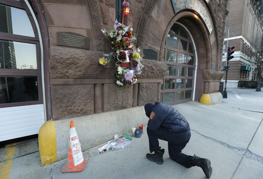 Somerville, Mass. firefighter Earl Johnson kneels to pray in front of a makeshift memorial on the front of fire station Engine 33, Thursday, March 27, 2014, in Boston. Fire station Engine 33 was the station of fallen firefighters Lt. Edward J. Walsh and Michael R. Kennedy who lost their lives fighting a 9-alarm fire in a four-story brownstone in Boston's Back Bay neighborhood Wednesday, March 26, 2014. (AP Photo/Steven Senne)