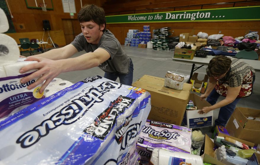 Volunteers, including Oliver Rankin, left, the son of Darrington Mayor Dan Rankin, and Laura Grimmer, right, sort items, Wednesday, March 26, 2014 that were donated to help families affected by the massive mudslide that struck near Darrington last Saturday. (AP Photo/Ted S. Warren)