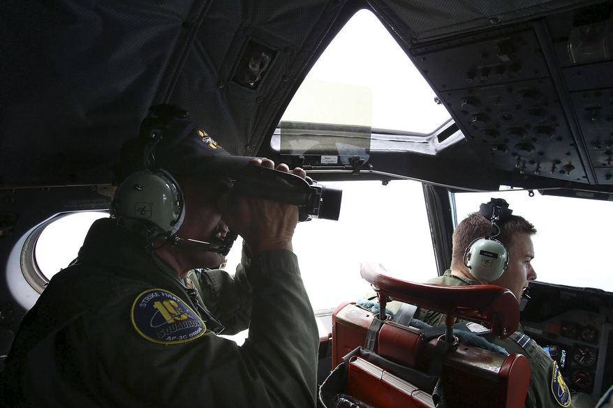 In this Wednesday, March 26, 2014 photo, Flight Engineer Ron Day on board a Royal Australian Air Force AP-3C Orion, seraches for the missing Malaysia Airlines Flight 370 in the southern Indian Ocean. A French satellite scanning the Indian Ocean for remnants of the missing jetliner found a possible plane debris field containing 122 objects, a top Malaysian official said Wednesday, calling it "the most credible lead that we have." (AP Photo/Paul Kane, Pool)