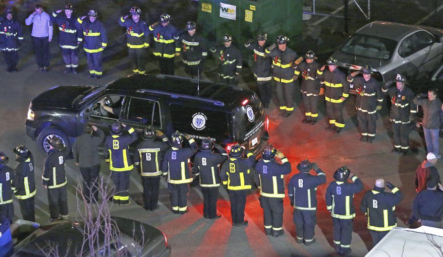 In this photo made Wednesday night, March 26, 2014, firefighters salute the medical examiner's truck carrying the body of one of two firefighters killed when a fire driven by strong winds whipped through a four-story apartment building in Boston and trapped them in the basement. (AP Photo/Boston Herald, Matt West) BOSTON GLOBE OUT. METRO BOSTON NEWSPAPER OUT. MAGS OUT. ONLINE OUT.
