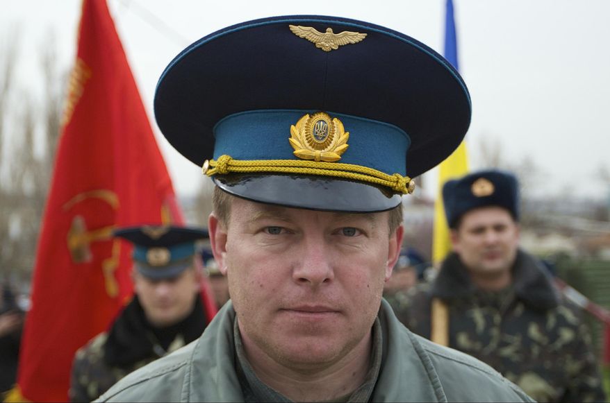 FILE - In this Tuesday, March 4, 2014 file photo, Air Force Col. Yuliy Mamchur, commander of the Ukrainian Belbek Air Base, leads his men to the base outside Sevastopol, Ukraine. The day after Crimeans voted to leave Ukraine and join Russia, a man in a black raincoat turned up at the gate of the Belbek Air Base to demand that the Ukrainian forces holed up inside surrender to Russia. The Ukrainian commander of the base came out proudly wearing his visor cap decorated with gold wings - and refused. Having withstood five days of sustained intimidation and pressure to defect from his captors, Mamchur now awaits a hero’s welcome in the capital, Kiev. (AP Photo/Ivan Sekretarev, File)