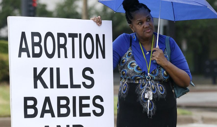 File-In this file photo made Monday, July 15, 2013, anti-abortion activist Teresa Steward of Desoto, Texas, stands on the curb sidewalk holding a sign in front of city hall as an abortions rights rally gets underway, in Dallas. A federal appeals court on Thursday March 27, 2014, upheld Texas' tough new abortion restrictions that shuttered many of the abortions clinics in the state. A panel of judges at the New Orleans-based 5th Circuit Court of Appeals overturned a lower court judge who said the rules violate the U.S. Constitution and served no medical purpose. In its opinion, the appeals court said the law "on its face does not impose an undue burden on the life and health of a woman." (AP Photo/Tony Gutierrez)