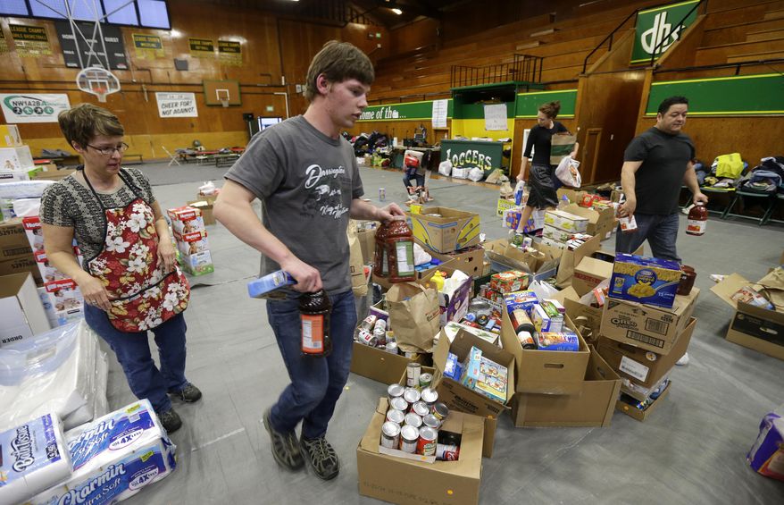 Volunteers, including Oliver Rankin, second from left, the son of Darrington Mayor Dan Rankin, and Laura Grimmer, left, sort items Wednesday, March 26, 2014 that were donated to help families affected by the massive mudslide that struck near Darrington last Saturday. (AP Photo/Ted S. Warren)