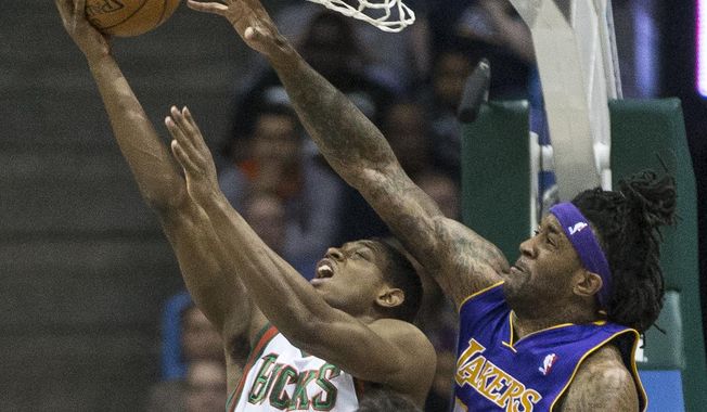 Milwaukee Bucks&#x27; Brandon Knight shoots a reverse lay-up as Los Angeles Lakers&#x27; Jordan Hill defends during the first half of an NBA basketball game Thursday, March 27, 2014, in Milwaukee. (AP Photo/Tom Lynn)