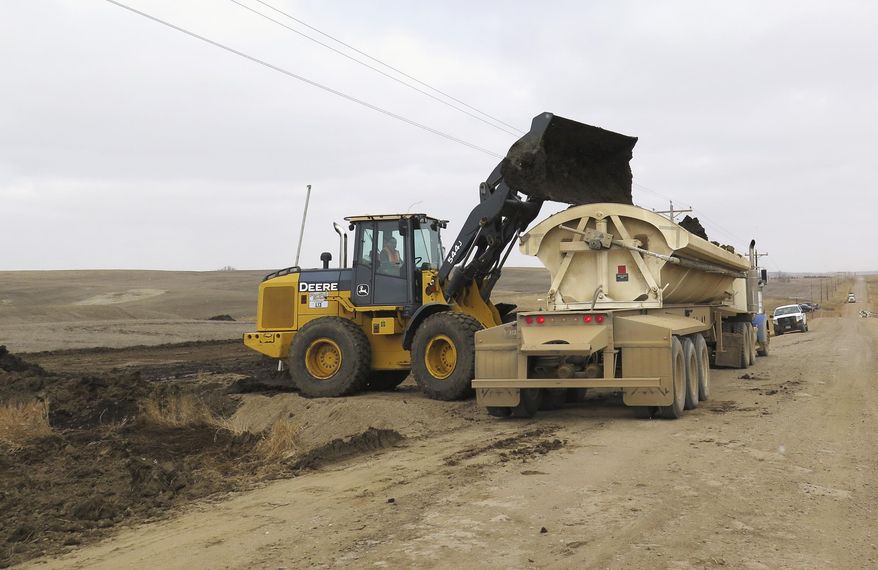 FILE - In this March 21, 2014 file photo, a clean-up crew loads dirt contaminated by an oil spill into trucks in Alexander, N.D., a day after a pipeline owned by Enid, Okla.-based Hiland Crude LLC broke, spewing about 34,000 gallons of crude oil. The North Dakota Health Department said Thursday, March 27, 2014, that cleanup is wrapping up at the oil spill site. (AP Photo/Josh Wood, File)