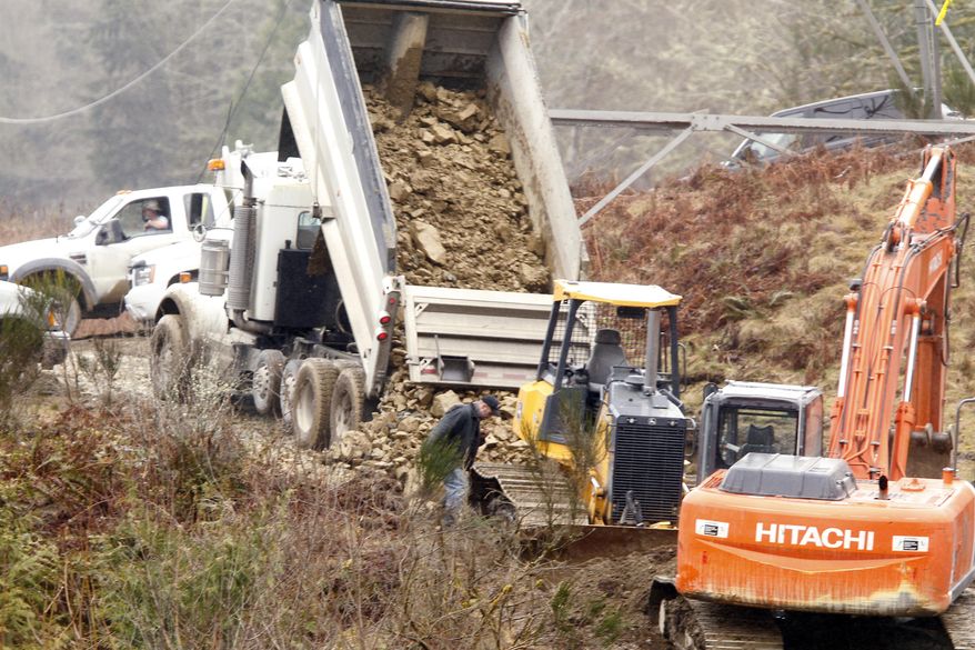 Workers build a temporary road to connect the two sides of a debris field from a deadly mudslide, Thursday, March 27, 2014, in Oso, Wash. The death toll is expected to rise considerably within the next two days as the Snohomish County Medical Examiner's Office catches up with the recovery effort, Snohomish County District 21 Fire Chief Travis Hots said Thursday. (AP Photo/The Herald, Mark Mulligan, Pool)