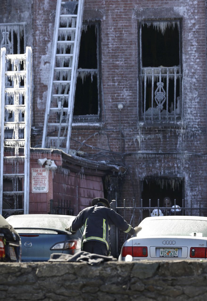 A firefighter pauses between cars near the burned remains of a four-story brownstone, Thursday, March 27, 2014, in Boston. Two firefighters, Lt. Edward Walsh and Michael Kennedy, lost their lives fighting a nine-alarm blaze that destroyed the structure in Boston's Back Bay neighborhood Wednesday, March 26, 2014. (AP Photo/Steven Senne)