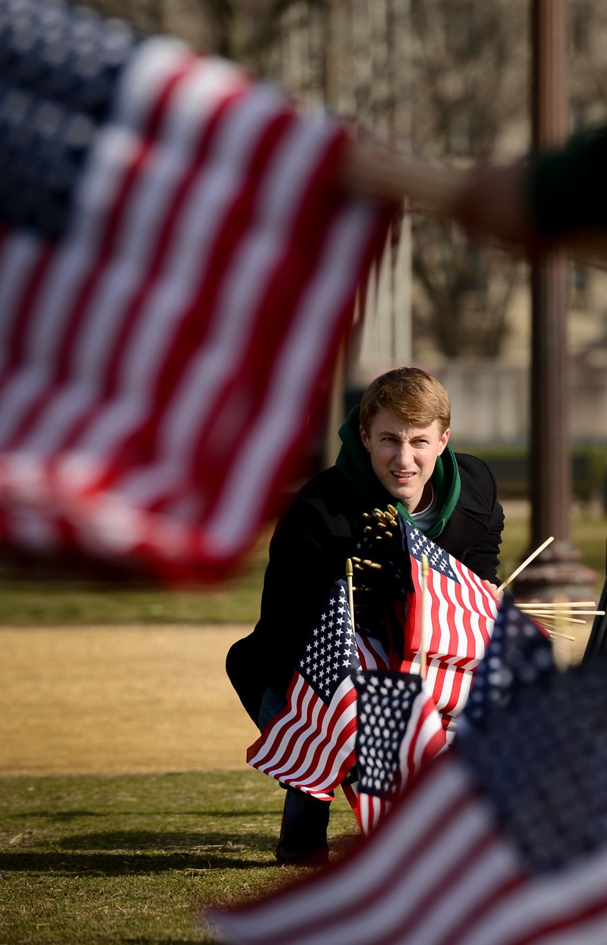 Army Veteran Sgt. Nick McCormick of Washington, D.C. helps line up a row of flags on the National Mall, Washington, D.C., Thursday, March 27, 2014. Veterans and supporters place American flags on the National Mall to represent each of the 1,892 veterans and service members who have died by suicide this year. (Andrew Harnik/The Washington Times)