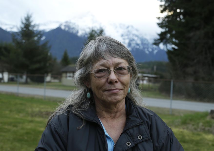 Robin Youngblood poses for a photo Thursday, March 27, 2014, with Whitehorse Mountain behind her in Darrington, Wash. Youngblood survived the massive mudslide that hit the nearby community of Oso, Wash. last Saturday, and was rescued by a helicopter as she floated on a piece of a roof. (AP Photo/Ted S. Warren)