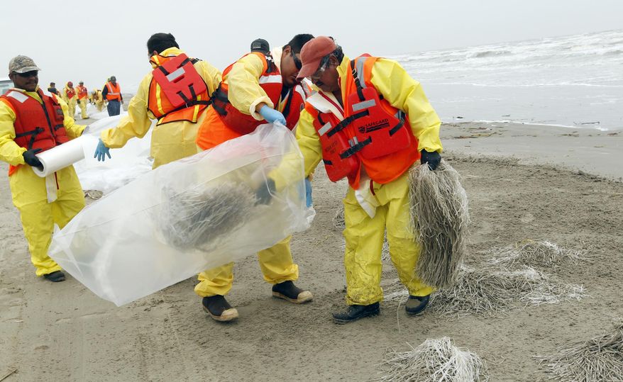 Oil spill response crews remove oil absorbent material placed on the beach between Stewart Beach and East Beach in Galveston on Thursday March 27, 2014. The material was placed on the stretch of beach as a precaution as cleanup continues after 168,000 gallons of heavy fuel oil spilled in to Galveston Bay on Saturday. (AP Photo/The Daily News, Jennifer Reynolds)