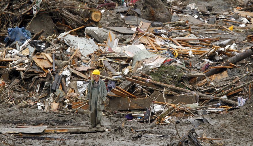 A searcher walks amidst a massive pile of debris at the scene of a deadly mudslide, Thursday, March 27, 2014, in Oso, Wash. The death toll is expected to rise considerably within the next two days as the Snohomish County Medical Examiner's Office catches up with the recovery effort, Snohomish County District 21 Fire Chief Travis Hots said Thursday. (AP Photo/The Herald, Mark Mulligan, Pool)